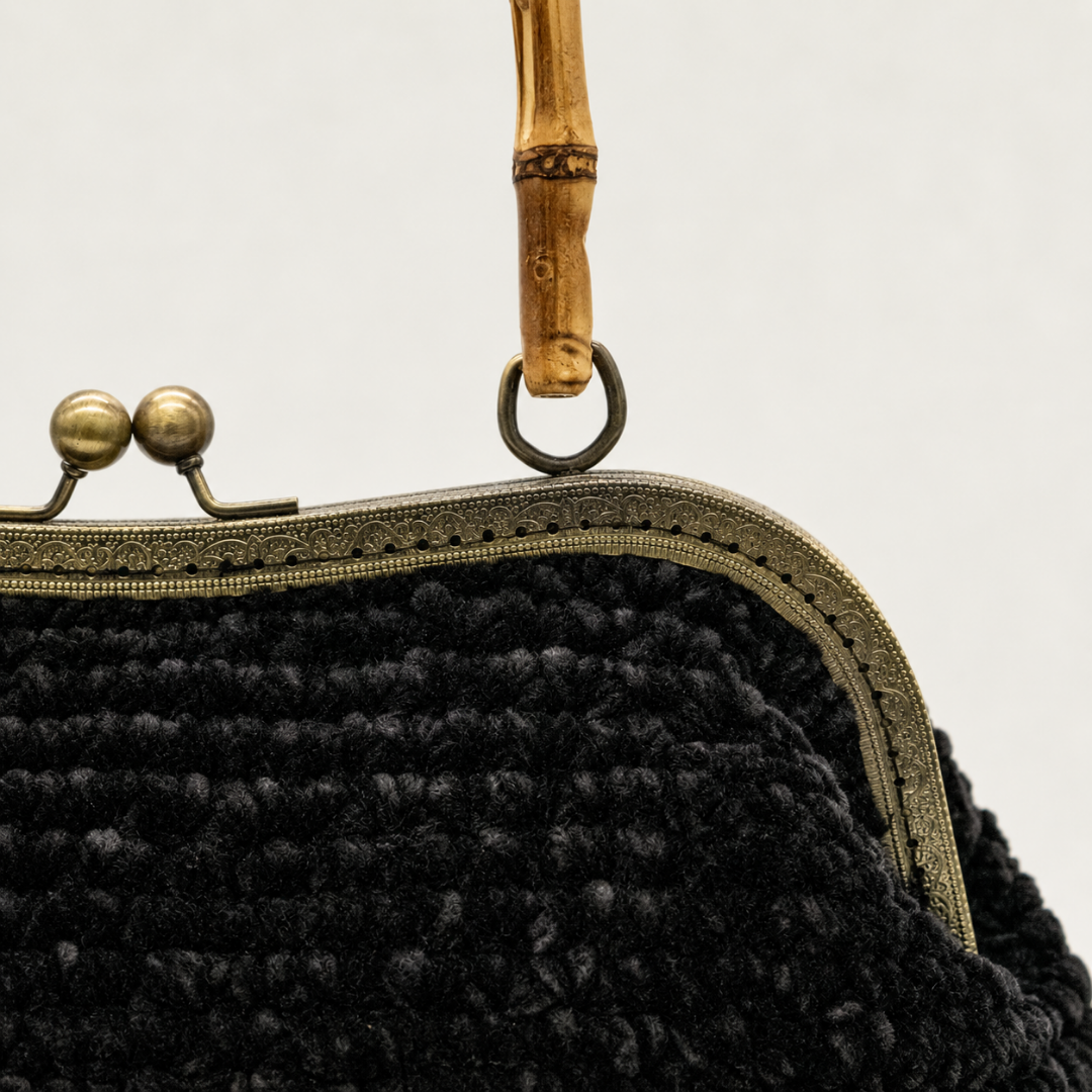 Dettaglio borsa artigianale nera in ciniglia con chiusura metallica vintage e manico in bambù