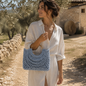 Borsa Nasitana azzurra indossata al braccio con manici dorati