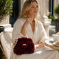 Borsa Rubino in ciniglia bordeaux indossata a spalla con look elegante
