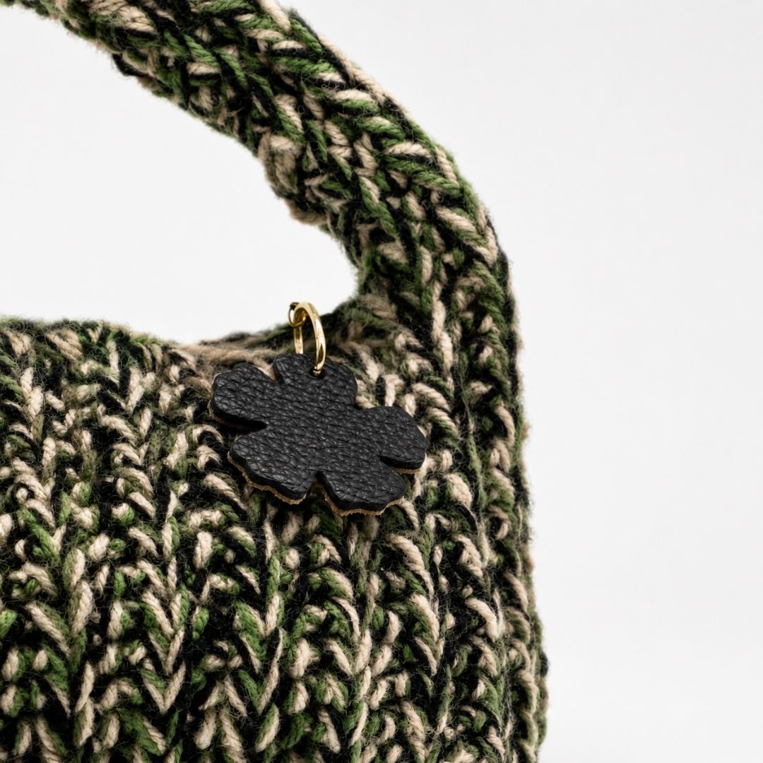 Dettaglio borsa Agata Verde con lavorazione intrecciata e pendente fiore nero