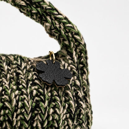 Dettaglio borsa Agata Verde con lavorazione intrecciata e pendente fiore nero