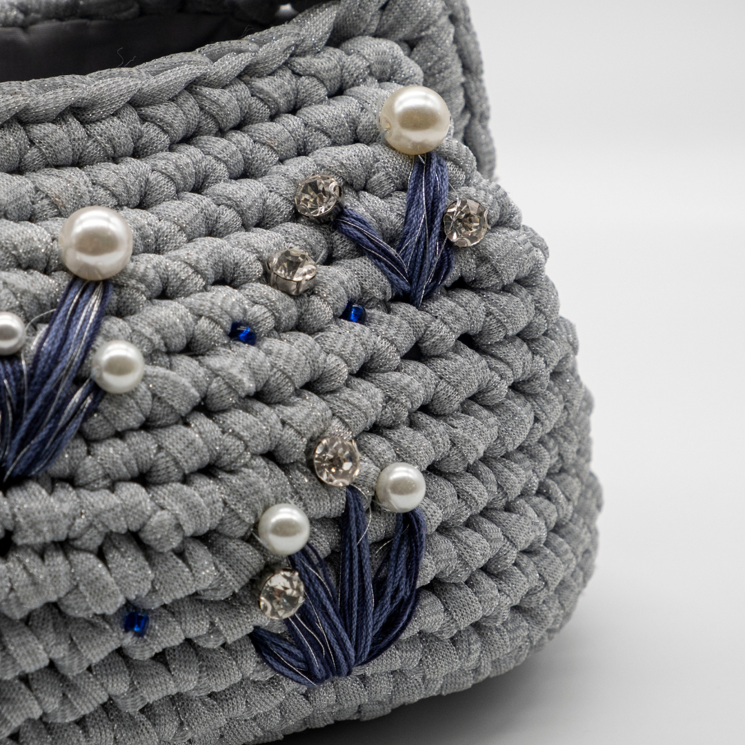 Dettaglio clutch artigianale grigio argento con perle, punti luce e ricami blu