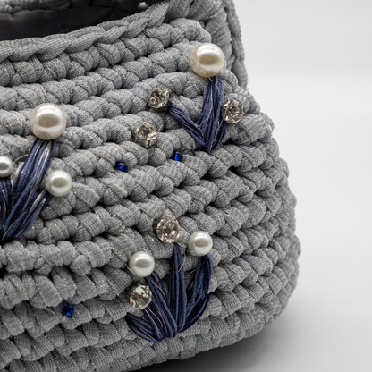 Dettaglio clutch artigianale grigio argento con perle, punti luce e ricami blu
